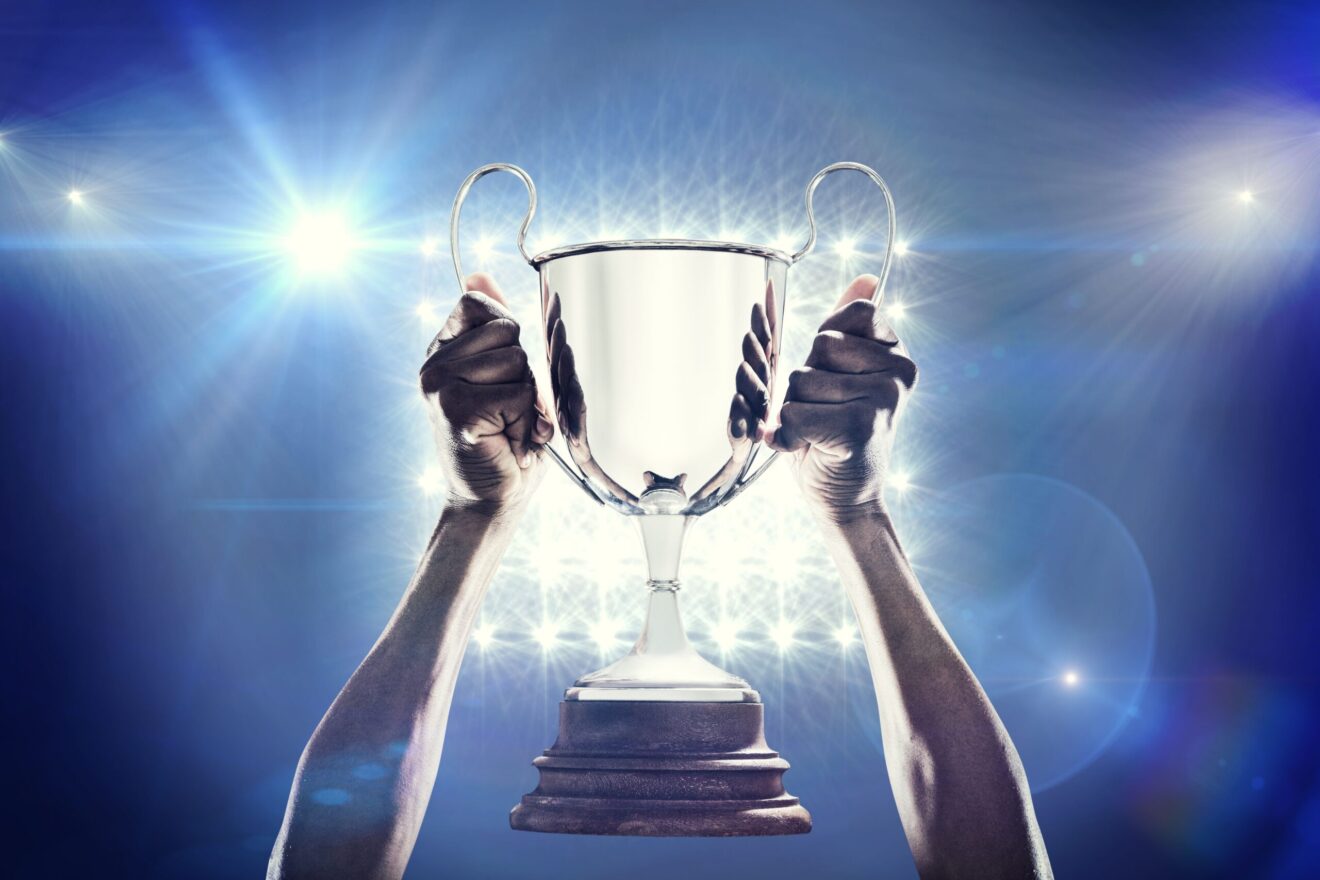 Cropped,Hand,Of,Athlete,Holding,Trophy,Against,Spotlights